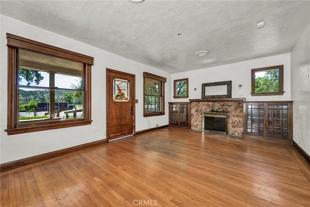21345 Bush St, Middletown, CA 95461 - unfurnished living room with hardwood / wood-style flooring, baseboards, a stone fireplace, plenty of natural light, and a textured ceiling