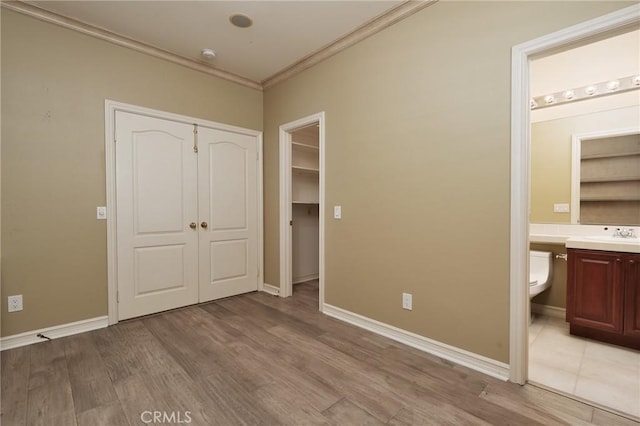 6471 Frampton Cir, Huntington Beach, CA 92648 - unfurnished bedroom featuring crown molding, a closet, light wood-style floors, and connected bathroom