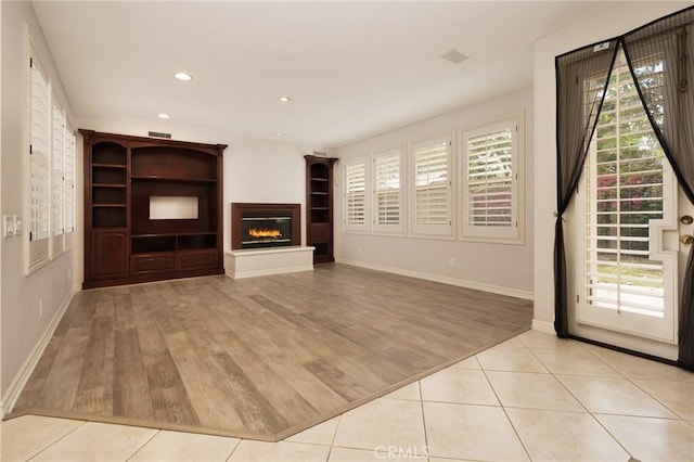 6471 Frampton Cir, Huntington Beach, CA 92648 - unfurnished living room with wood finished floors, a glass covered fireplace, recessed lighting, and built in shelves