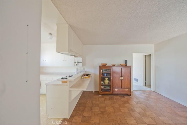 16751 Ludlow St, Granada Hills, CA 91344 - kitchen with light countertops, white cabinets, a peninsula, a textured ceiling, and white gas cooktop