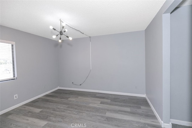 28031 Sarabande Ln Unit 128, Canyon Country, CA 91387 - spare room with wood finished floors, a textured ceiling, a chandelier, and baseboards