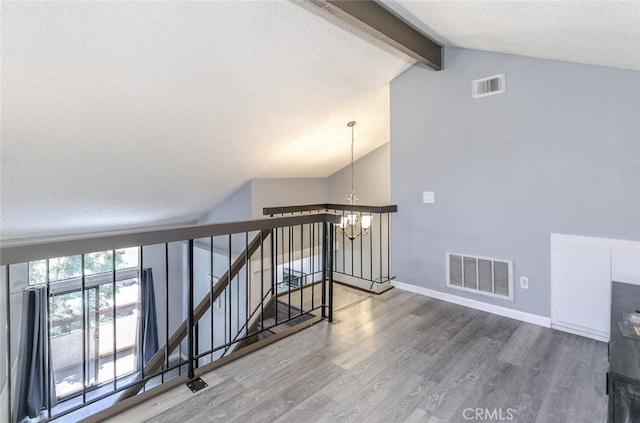 28031 Sarabande Ln Unit 128, Canyon Country, CA 91387 - staircase with a chandelier, a textured ceiling, wood finished floors, and baseboards