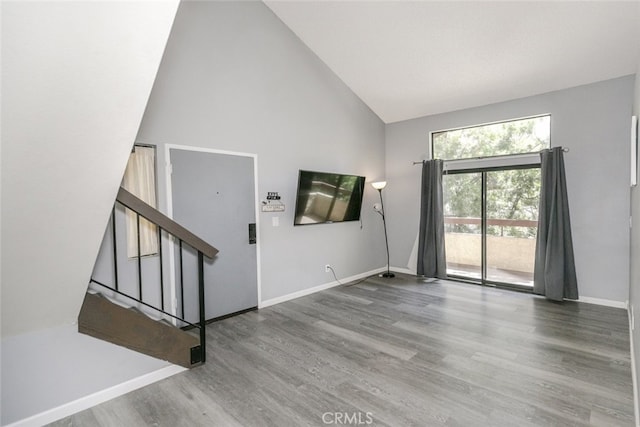 28031 Sarabande Ln Unit 128, Canyon Country, CA 91387 - unfurnished living room featuring high vaulted ceiling, wood finished floors, baseboards, and stairway