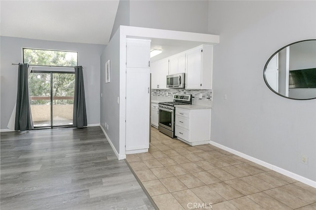 28031 Sarabande Ln Unit 128, Canyon Country, CA 91387 - kitchen with appliances with stainless steel finishes, high vaulted ceiling, white cabinetry, tasteful backsplash, and light countertops