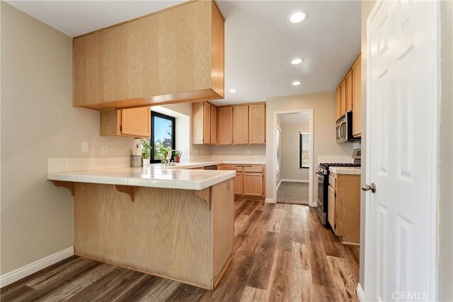 5809 Almond Valley Way, Lancaster, CA 93536 - kitchen with appliances with stainless steel finishes, a peninsula, baseboards, tile counters, and wood finished floors