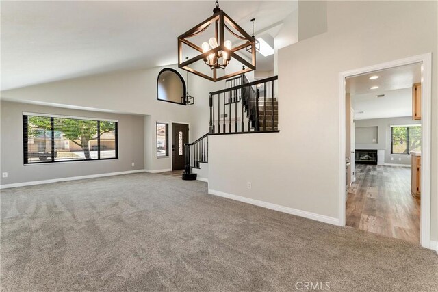 5809 Almond Valley Way, Lancaster, CA 93536 - unfurnished living room featuring carpet floors, stairs, a chandelier, high vaulted ceiling, and baseboards
