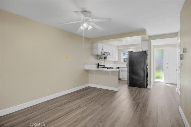 1881 Mitchell Ave Unit 34, Tustin, CA 92780 - kitchen with freestanding refrigerator, open shelves, a peninsula, under cabinet range hood, and light countertops