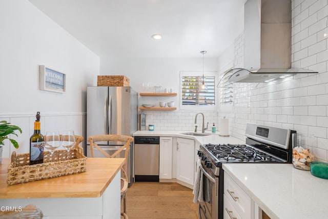 244 Cahuenga Dr, Oxnard, CA 93035 - kitchen featuring wall chimney range hood, stainless steel appliances, a sink, light wood-style flooring, and white cabinets