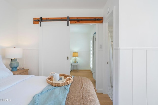 244 Cahuenga Dr, Oxnard, CA 93035 - bedroom with light wood-style floors, a wainscoted wall, and a barn door