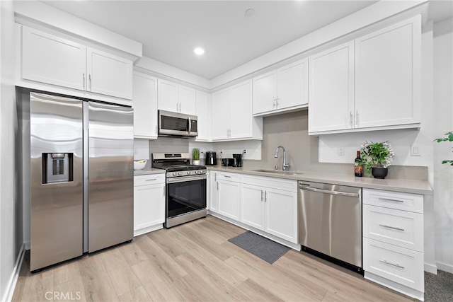 466 Besalu, Mission Viejo, CA 92692 - kitchen featuring appliances with stainless steel finishes, a sink, white cabinetry, light wood-type flooring, and light countertops