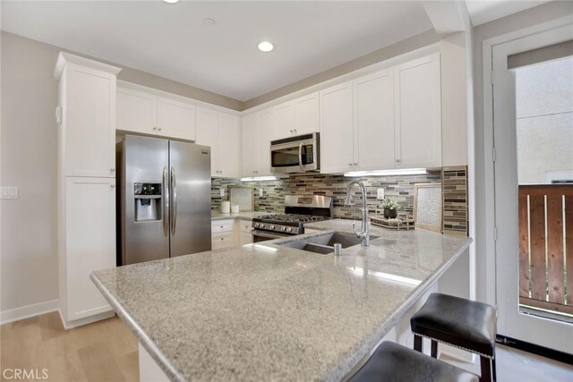 908 N Alameda Ave, Azusa, CA 91702 - kitchen featuring stainless steel appliances, a peninsula, backsplash, white cabinetry, and light stone countertops