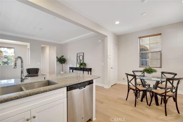 908 N Alameda Ave, Azusa, CA 91702 - kitchen with stainless steel dishwasher, a sink, white cabinets, light stone counters, and light wood-style floors