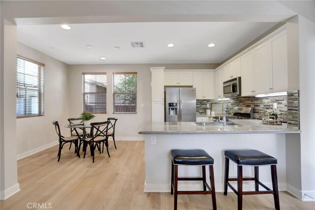 908 N Alameda Ave, Azusa, CA 91702 - kitchen featuring appliances with stainless steel finishes, a peninsula, white cabinets, light wood finished floors, and baseboards