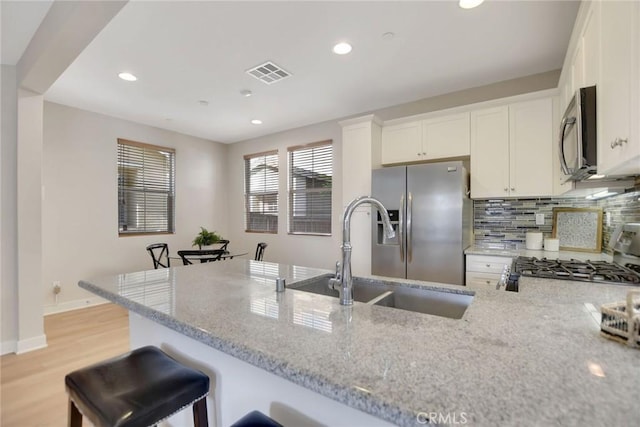 908 N Alameda Ave, Azusa, CA 91702 - kitchen with appliances with stainless steel finishes, light stone countertops, a sink, decorative backsplash, and white cabinets