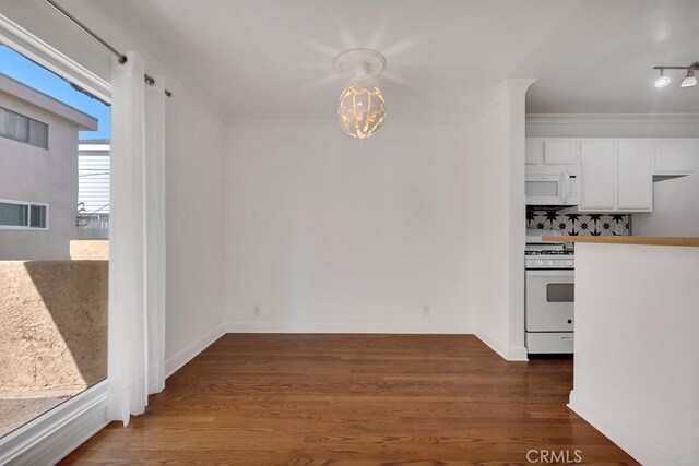 1020 Granville Ave Unit 205, Los Angeles, CA 90049 - unfurnished dining area featuring dark wood-style flooring, crown molding, and a chandelier