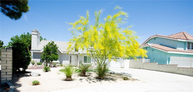5515 Katrina Pl, Palmdale, CA 93552 - view of front facade with concrete driveway, stucco siding, a tile roof, a chimney, and an attached garage