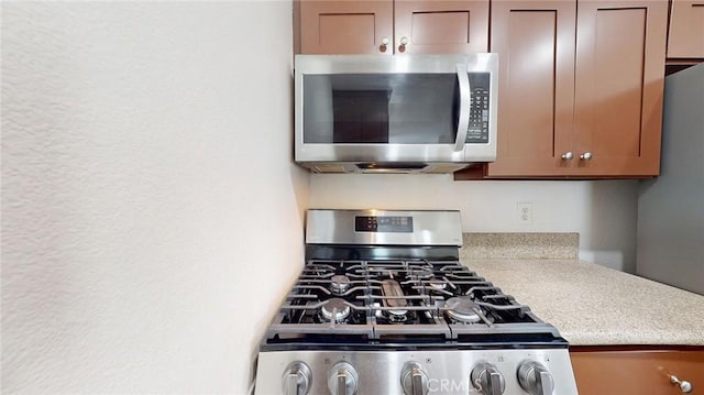 24420 Flaxwood Ln Unit 204, Newhall, CA 91321 - kitchen view of appliances with stainless steel finishes, light countertops, and a textured wall