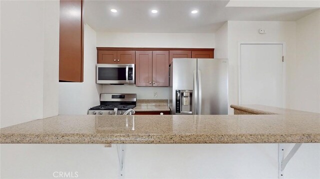 24420 Flaxwood Ln Unit 204, Newhall, CA 91321 - kitchen featuring stainless steel appliances, light stone counters, recessed lighting, and a peninsula