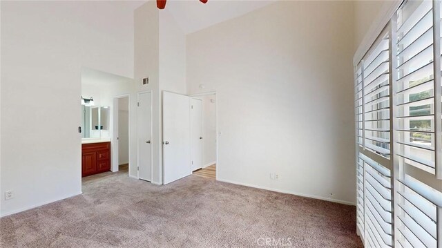24420 Flaxwood Ln Unit 204, Newhall, CA 91321 - unfurnished bedroom with multiple windows, light colored carpet, high vaulted ceiling, baseboards, and connected bathroom