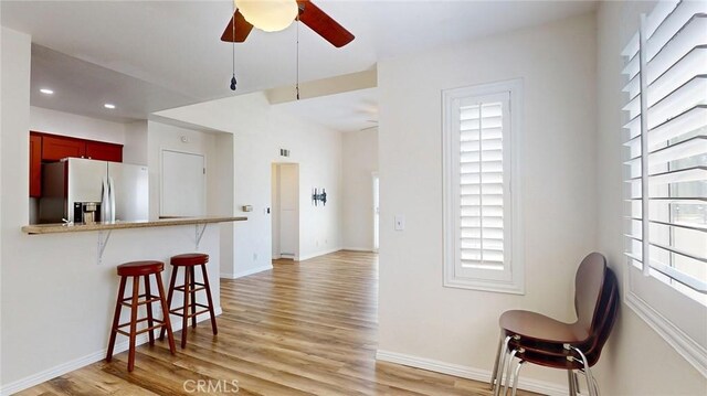 24420 Flaxwood Ln Unit 204, Newhall, CA 91321 - kitchen with stainless steel fridge, a kitchen bar, light wood-type flooring, a ceiling fan, and baseboards