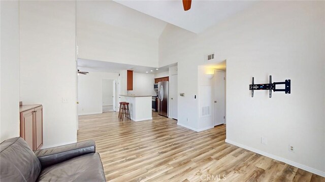 24420 Flaxwood Ln Unit 204, Newhall, CA 91321 - unfurnished living room featuring a ceiling fan, light wood finished floors, baseboards, and a towering ceiling