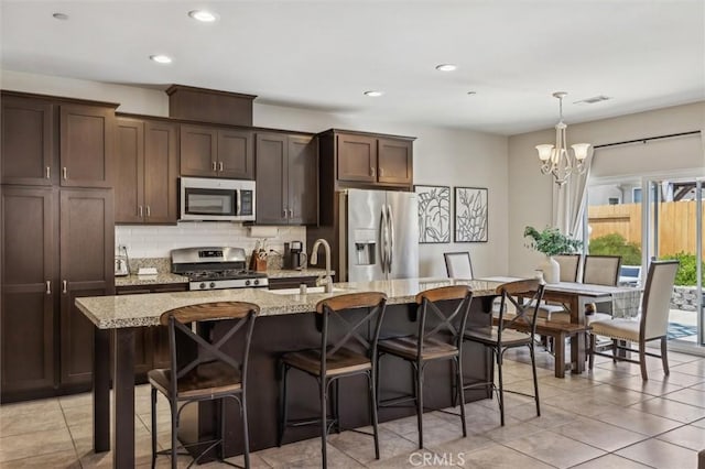 255 Waterfall Rd, Templeton, CA 93465 - kitchen featuring appliances with stainless steel finishes, a sink, light tile patterned floors, tasteful backsplash, and a breakfast bar
