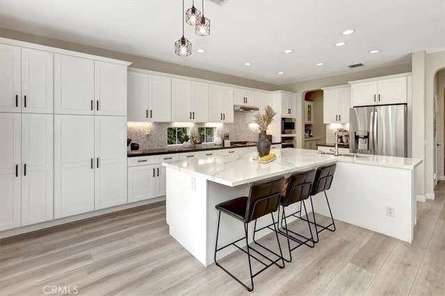 19 Laurelhurst Dr, Ladera Ranch, CA 92694 - kitchen featuring stainless steel refrigerator with ice dispenser, a sink, arched walkways, a large island with sink, and recessed lighting