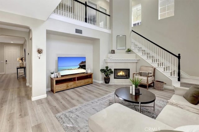 19 Laurelhurst Dr, Ladera Ranch, CA 92694 - living area featuring wood finished floors, stairway, baseboards, a glass covered fireplace, and a towering ceiling