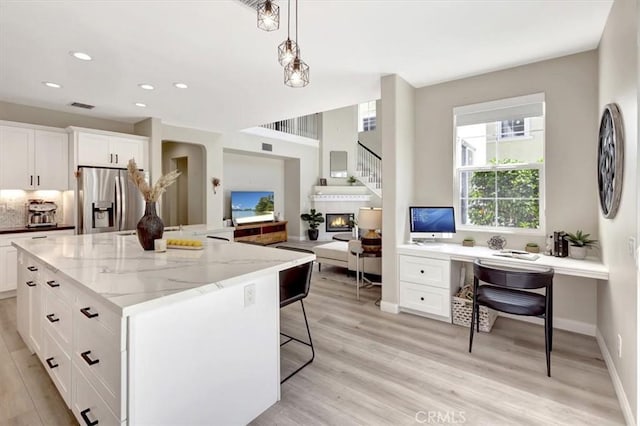 19 Laurelhurst Dr, Ladera Ranch, CA 92694 - kitchen with stainless steel refrigerator with ice dispenser, light wood finished floors, a kitchen bar, white cabinets, and recessed lighting