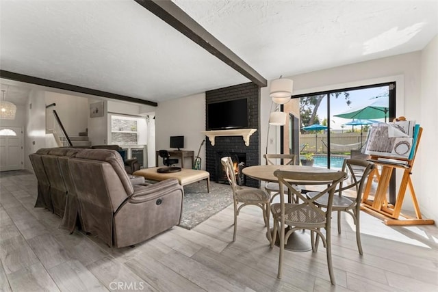 1520 Downs St, Oceanside, CA 92054 - living room featuring a brick fireplace, stairway, light wood finished floors, beam ceiling, and a textured ceiling