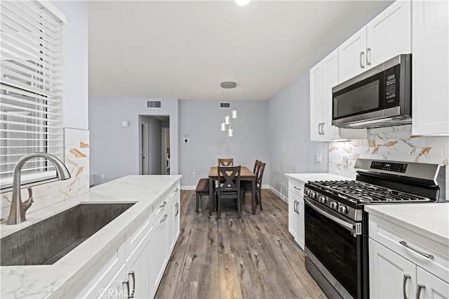 20000 Plum Canyon Rd Unit 1326, Saugus, CA 91350 - kitchen featuring appliances with stainless steel finishes, a sink, backsplash, light wood-style floors, and white cabinetry