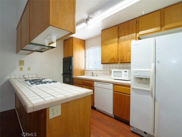 3819 W 190th St, Torrance, CA 90504 - kitchen featuring white appliances, tile counters, wood finished floors, a peninsula, and backsplash