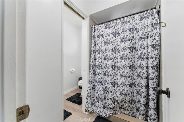 1089 E Columbia Ave, Pomona, CA 91767 - bathroom with toilet, wood finished floors, a shower with shower curtain, and baseboards