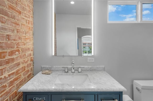 4275 Country Club Dr, Long Beach, CA 90807 - bathroom featuring toilet, vanity, and brick wall