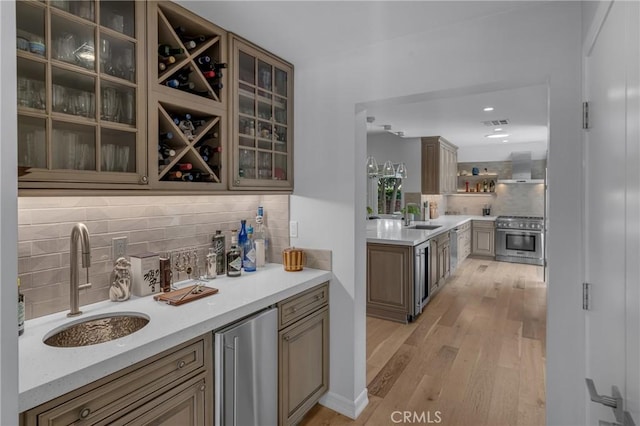 4275 Country Club Dr, Long Beach, CA 90807 - bar area featuring stainless steel stove, a sink, backsplash, wall chimney exhaust hood, and light wood-type flooring