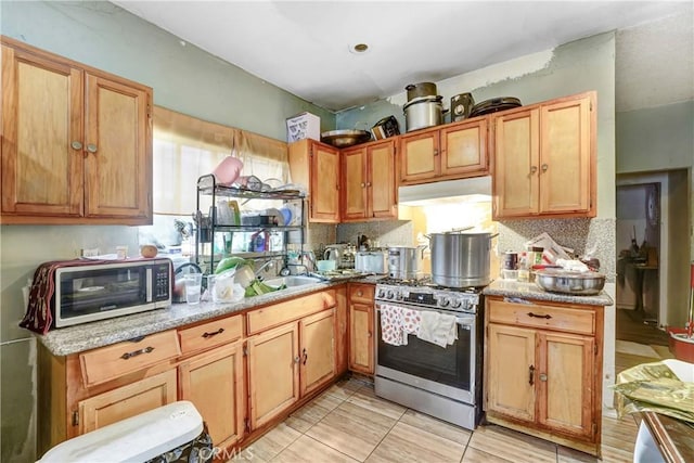 1132 E 53rd St, Los Angeles, CA 90011 - kitchen with gas range, under cabinet range hood, tasteful backsplash, and light stone counters