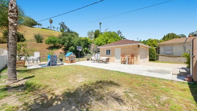 686 W 34th St, San Bernardino, CA 92405 - view of grassy yard with a playground, a detached garage, a patio, and an outdoor structure