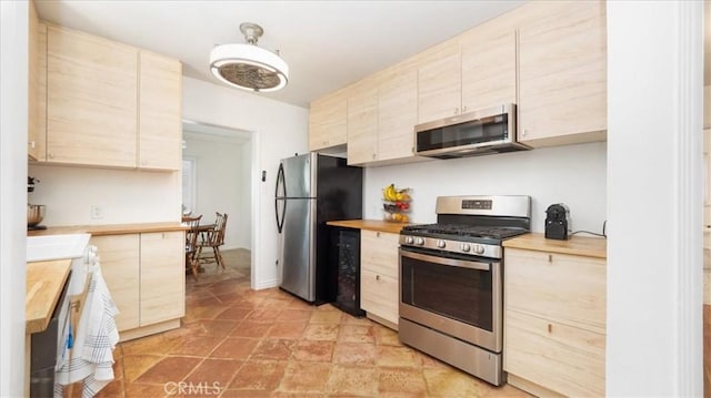 686 W 34th St, San Bernardino, CA 92405 - kitchen featuring stainless steel appliances, light brown cabinets, light stone finish floors, and wooden counters
