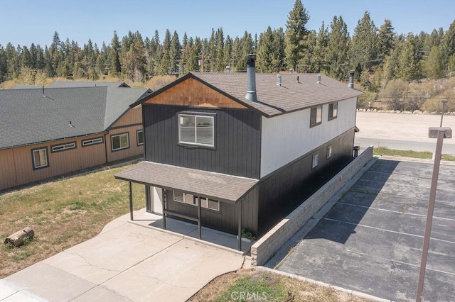 42692 Moonridge Rd, Big Bear Lake, CA 92315 - back of property featuring a shingled roof, a view of trees, a lawn, and a porch