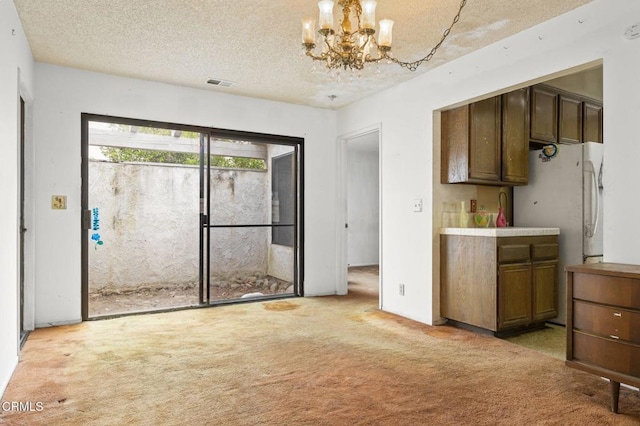 201 Village Rd, Port Hueneme, CA 93041 - kitchen featuring light colored carpet, freestanding refrigerator, a chandelier, and a textured ceiling