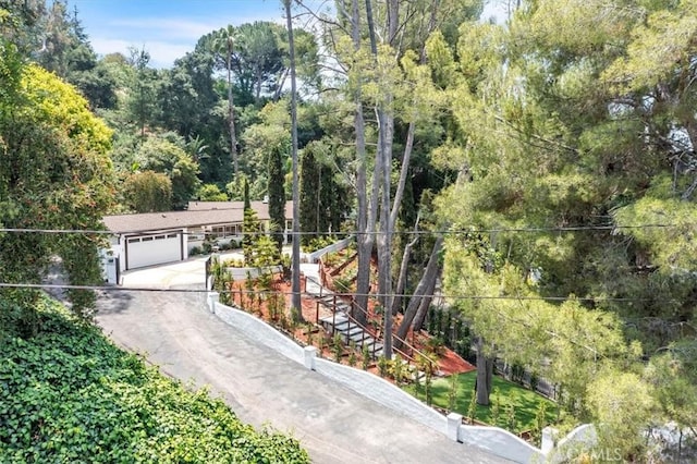 9466 Hidden Valley Pl, Beverly Hills, CA 90210 - view of front of home with driveway, a view of trees, and an attached garage