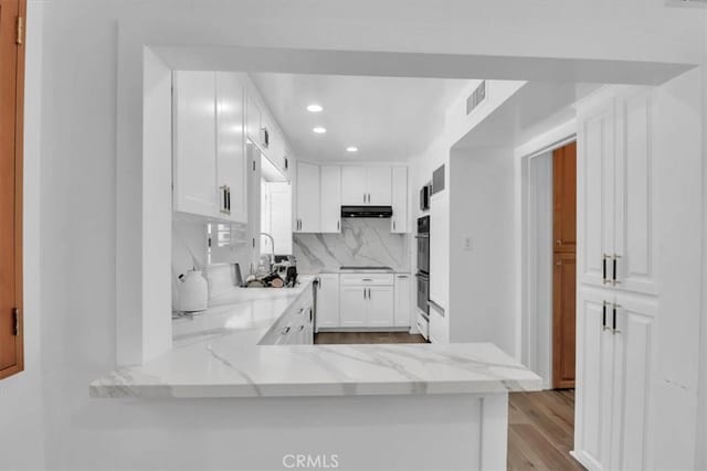 9466 Hidden Valley Pl, Beverly Hills, CA 90210 - kitchen with recessed lighting, white cabinetry, decorative backsplash, light stone countertops, and black appliances