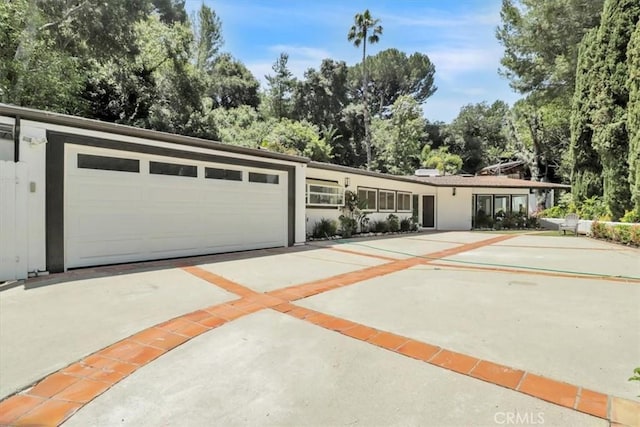 9466 Hidden Valley Pl, Beverly Hills, CA 90210 - view of front of property with concrete driveway, view of wooded area, and an attached garage