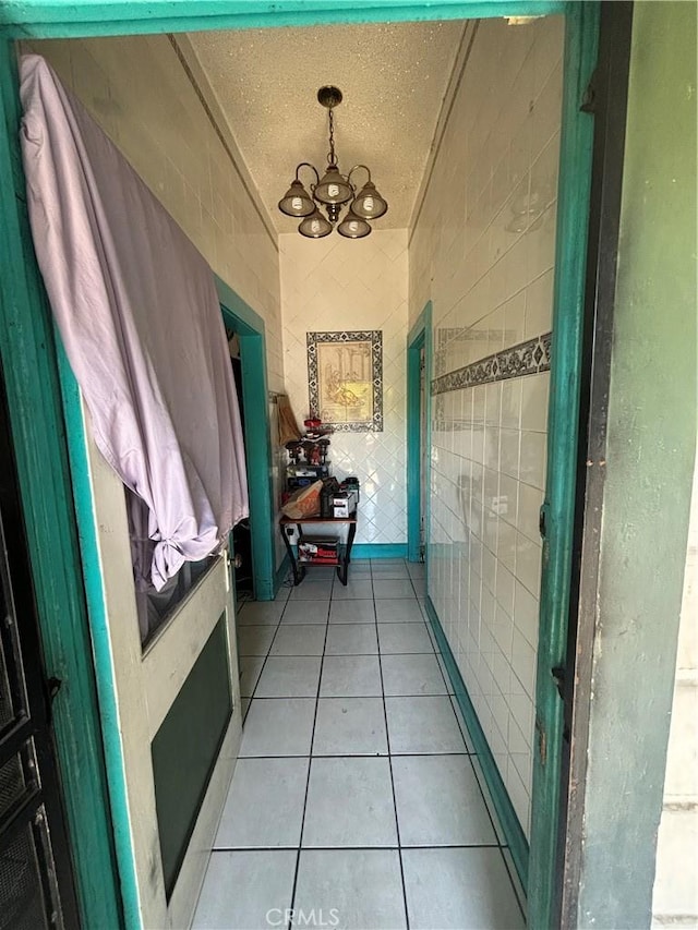 223 E 28th St, Los Angeles, CA 90011 - corridor with a chandelier, light tile patterned flooring, a textured ceiling, and tile walls