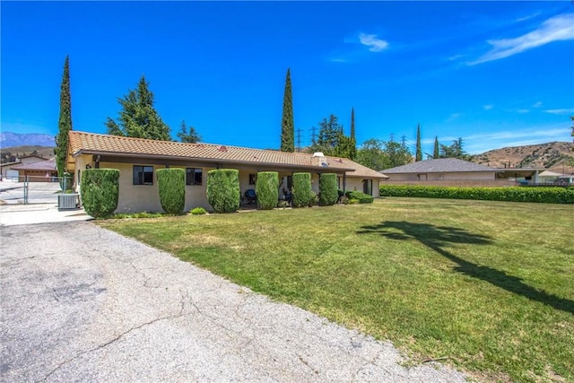 4256 Mockingbird Ln, Banning, CA 92220 - view of front of house featuring a front yard, stucco siding, a tiled roof, central AC unit, and a mountain view