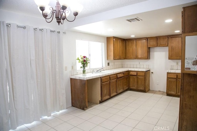 1003 Lightcap St, Lancaster, CA 93535 - kitchen featuring brown cabinetry, tile counters, a sink, a chandelier, and recessed lighting