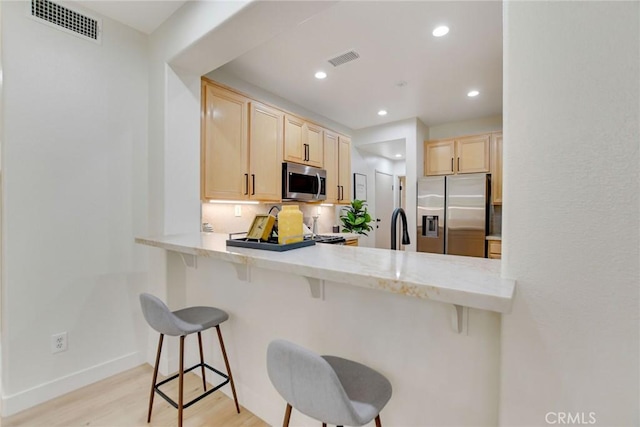 28210 Canterbury Ct, Valencia, CA 91354 - kitchen featuring appliances with stainless steel finishes, light brown cabinets, light countertops, light wood-style flooring, and a peninsula