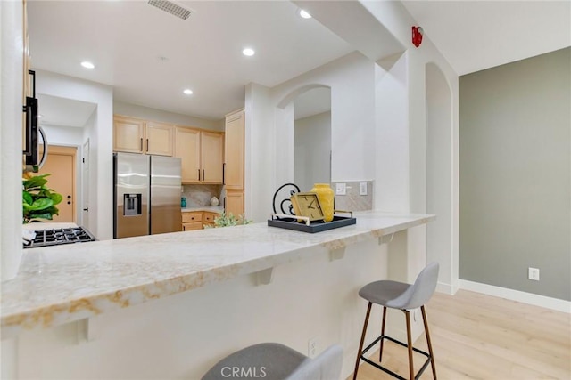 28210 Canterbury Ct, Valencia, CA 91354 - kitchen featuring appliances with stainless steel finishes, light brown cabinetry, a peninsula, light wood-type flooring, and light stone countertops