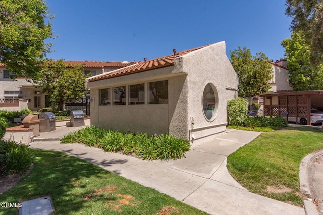 1742 Sinaloa Rd Unit 329, Simi Valley, CA 93065 - view of front of home with exterior kitchen, stucco siding, a front lawn, and a tiled roof