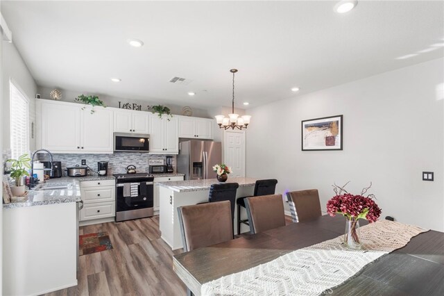 20793 Spring Mountain Rd, Riverside, CA 92507 - kitchen with appliances with stainless steel finishes, a sink, a chandelier, a kitchen island, and wood finished floors